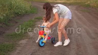 妈妈教女儿骑自行车。 姐姐和一个小孩子玩。 快乐童年的概念.. 一个小孩学